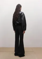 Pantalón de vestir negro estilo flare de tiro medio, con trabillas y cierre frontal con botón, gancho y cremallera.