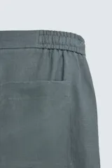 Bermuda de lino color blanco hueso, de corte relajado y tiro medio. Presenta cintura elástica ajustable con cordón, pliegues frontales y bolsillos laterales y trasero.