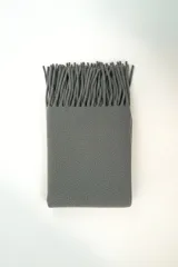 Poncho gris liso con flecos largos en el borde superior.