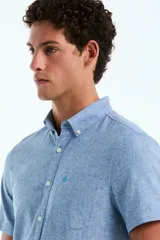 Camisa de manga corta de lino y algodón color celeste melange, con cuello abotonado, cierre frontal de botones y bolsillo ojal en el pecho con el logo bordado.