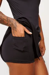 Vestido deportivo negro sin mangas, con escote en V y logo estampado en el pecho. Falda corta con short interno y bolsillos laterales. Incluye protección UV50+.