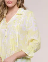Blusa celeste con estampado efecto pincelada blanca, de corte semi holgado, escote en V con cuello solapa y media abotonadura frontal con botones nacarados. Presenta finas alforzas verticales en la pechera y mangas 3/4 con puños elastizados.