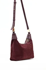 Cartera tipo hobo de Lolita, confeccionada en gamuza color bordó, con diseño de asa integrada y cierre superior. Presenta detalles en cuero liso en los extremos del asa y logo de la marca grabado en el frente.