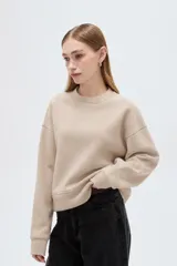Buzo de cuello redondo color beige claro, de manga larga y diseño holgado con felpa interior.