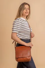 Bandolera de diseño simple con tapa frontal, confeccionada en material símil cuero. Cuenta con correa ajustable, división interna y bolsillos internos para mayor organización.