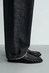 Mocasín de vestir negro, con acabado liso y brillante, puntera cuadrada y detalle de antifaz en el empeine. Posee suela fina y tacón bajo.