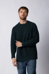 Sweater de punto grueso en color verde oscuro, con cuello redondo y mangas raglán. Presenta un ajuste relajado y puños acanalados con un pequeño detalle de etiqueta de marca.