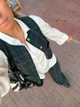 Chaleco de corte clásico con estampado de cuadros en tonos verde oscuro y azul marino. Presenta cierre frontal con botones claros y bolsillos laterales.