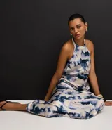 Vestido largo estilo slip con cuello halter que se ata en la nuca, sin mangas, con estampado abstracto en tonos azul y blanco que simula un efecto tie-dye.