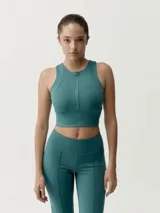 Top deportivo color beige, de cuello redondo con cierre frontal parcial y diseño ajustado.