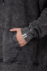 Buzo canguro oversize de algodón friza con efecto de teñido artesanal desgastado. Presenta capucha con cordones negros, bolsillo frontal tipo canguro y estampa pequeña de Popeye en el pecho.