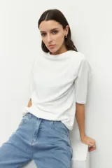 Remera negra de cuello redondo y manga tres cuartos, confeccionada en tela con textura sutil. Presenta fruncidos laterales que aportan caída y movimiento a la prenda.