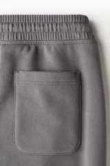Pantalón deportivo de felpa con interior cepillado, corte relajado, cintura elástica con cordón de ajuste, bolsillos laterales y puños acanalados en los tobillos.
