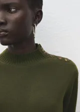 Vestido corto de punto color verde militar, con cuello alto, mangas largas y detalle de botones dorados en el hombro.