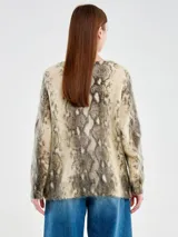 Cardigan de punto con escote en V y cierre frontal de botones. Presenta un diseño de animal print tipo serpiente en tonos beige, marrón y gris, con un calce relajado y textura suave.