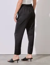 Pantalón negro de satén con pretina elastizada, lazo de ajuste y bolsillos inclinados.