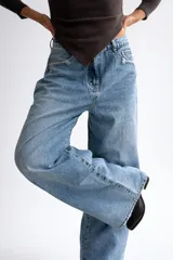 Pantalón de jean estilo palazzo en tono celeste medio, con corte amplio y tiro medio. Presenta sutiles detalles de roturas en los bolsillos y en el ruedo deshilachado.