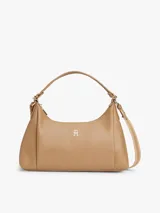 Cartera tipo hobo de Tommy Hilfiger en color beige, con acabado liso, cierre de cremallera, asa superior y correa ajustable y extraíble. Cuenta con el logo metálico de la marca en relieve en la parte delantera.