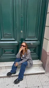 Blazer gris con solapas de muesca, bolsillos con solapa en el frente y un botón de cierre.