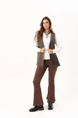 Chaleco de cuero marrón con silueta relajada, caracterizado por detalles de ojalillos metálicos a lo largo de los bordes frontales.