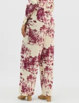 Conjunto de dos piezas compuesto por camisa de manga larga con cuello solapa y botones frontales, y pantalón de tiro alto con pierna recta y bolsillos laterales. Ambas prendas presentan un estampado paisajístico en tonos marrones sobre fondo crema.