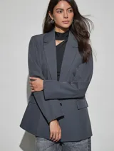 Blazer gris oscuro de corte recto y holgado, con solapas de muesca, un botón frontal y bolsillos con solapa en los laterales.