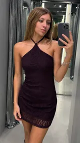 Vestido corto ajustado al cuerpo, con escote halter y diseño de encaje con textura. Presenta un acabado elegante ideal para eventos nocturnos.