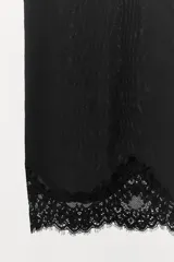 Falda tipo media de tiro medio y cintura elástica, color negro. El bajo está acabado con una aplicación de encaje combinado a tono.