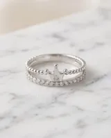 Anillo de plata 925 con diseño de corona y detalles de circonias cúbicas brillantes, acompañado por una alianza fina decorada con pequeñas piedras incrustadas.