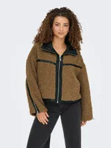 Campera de textura tipo teddy color marrón, con detalles en cuero sintético negro en el cuello, cierre frontal y mangas. Presenta cierre en los puños y diseño de corte recto.