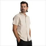 Camisa de lino color beige, de manga corta, con cuello clásico y cierre frontal con botones.