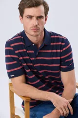 Remera polo de manga corta con diseño de rayas horizontales en color azul marino y rosado. Cuenta con cuello camisero, cierre frontal con botones y calce clásico.