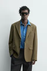 Blazer regular fit de Zara Origins, confeccionada en tejido de lana y algodón color verde militar. Presenta cuello con solapas de muesca, cierre frontal de un botón, bolsillos de solapa en la cadera y bolsillo de vivo en el pecho.