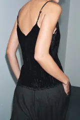 Top de terciopelo negro con escote en pico, tirantes finos ajustables y detalles de encaje a tono en el escote y el bajo.