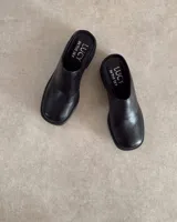 Zueco de cuero negro con punta redondeada y taco cuadrado de 4.5 cm. Diseño tipo mule con plantilla acolchada y marca Lucy in the Sky.