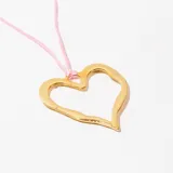 Collar dorado con dije en forma de corazón irregular y cordón fino color rosa.
