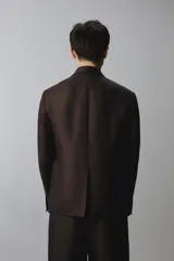 Blazer cruzada de hombre en color marrón oscuro, de corte regular fit, confeccionada en lino. Cuenta con solapas de muesca, bolsillos con solapa en la cadera y doble botonadura frontal.