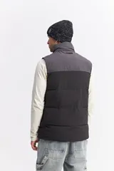 Chaleco puffer bicolor con diseño en bloques, cierre frontal y bolsillos funcionales. Presenta un ajuste regular y logo de la marca estampado en el pecho.