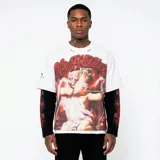 Camiseta blanca de corte oversize con estampado gráfico frontal de un cupido vendado y la inscripción 'Life Hustlers'. Presenta detalles de desgaste en el cuello y mangas, y se muestra superpuesta sobre una prenda de manga larga negra con estampados laterales en rojo.