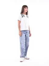 Remera blanca de manga corta con cuello redondo, destacada por apliques bordados con lentejuelas en los hombros.