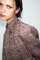 Blazer de lana con diseño de cuadros, cuello subido, manga larga, bolsillos delanteros y cierre frontal cruzado con un botón.