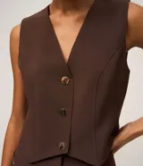 Chaleco slim color marrón, confeccionado en crepé, con escote en V y cierre frontal de botones metálicos.