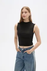 Top cropped negro de algodón, con cuello alto y diseño ajustado al cuerpo con frunces laterales.