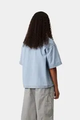 Camisa de denim de algodón celeste, de corte holgado y mangas cortas, con cierre frontal de botones metálicos y un bolsillo aplicado en el pecho con etiqueta de la marca.