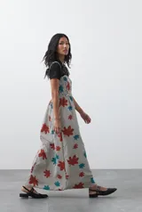 Vestido midi de corte fluido con cuerpo superior fruncido, escote recto y tiras finas regulables. Presenta un diseño estampado con hojas en tonos rojos y turquesas sobre una base de rayas verticales finas.