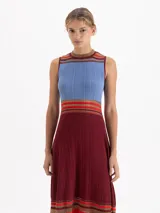 Vestido midi de punto sin mangas con diseño plisado. Presenta un corte evasé con rayas horizontales en tonos rojo, rosa y negro en el cuello, la cintura y el ruedo, el cual cuenta con terminaciones irregulares y detalles de transparencia.