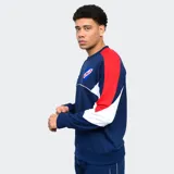 Buzo de cuello redondo azul marino con mangas rojas y paneles blancos en los laterales. Presenta el logo de Umbro bordado en blanco y el escudo del Club Nacional de Football bordado en el pecho. Corte clásico.