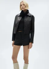 Top de punto fino color negro, con diseño entallado, cuello alto y sin mangas.