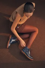 Bota acordonada de cuero vacuno con acabado charol color suela, con suela de goma tipo crepe y costuras reforzadas.