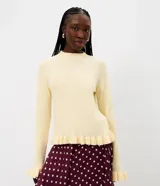 Suéter de tricot color amarillo claro, de manga larga y cuello redondo. Presenta detalles de volados acanalados en el ruedo y en los puños.